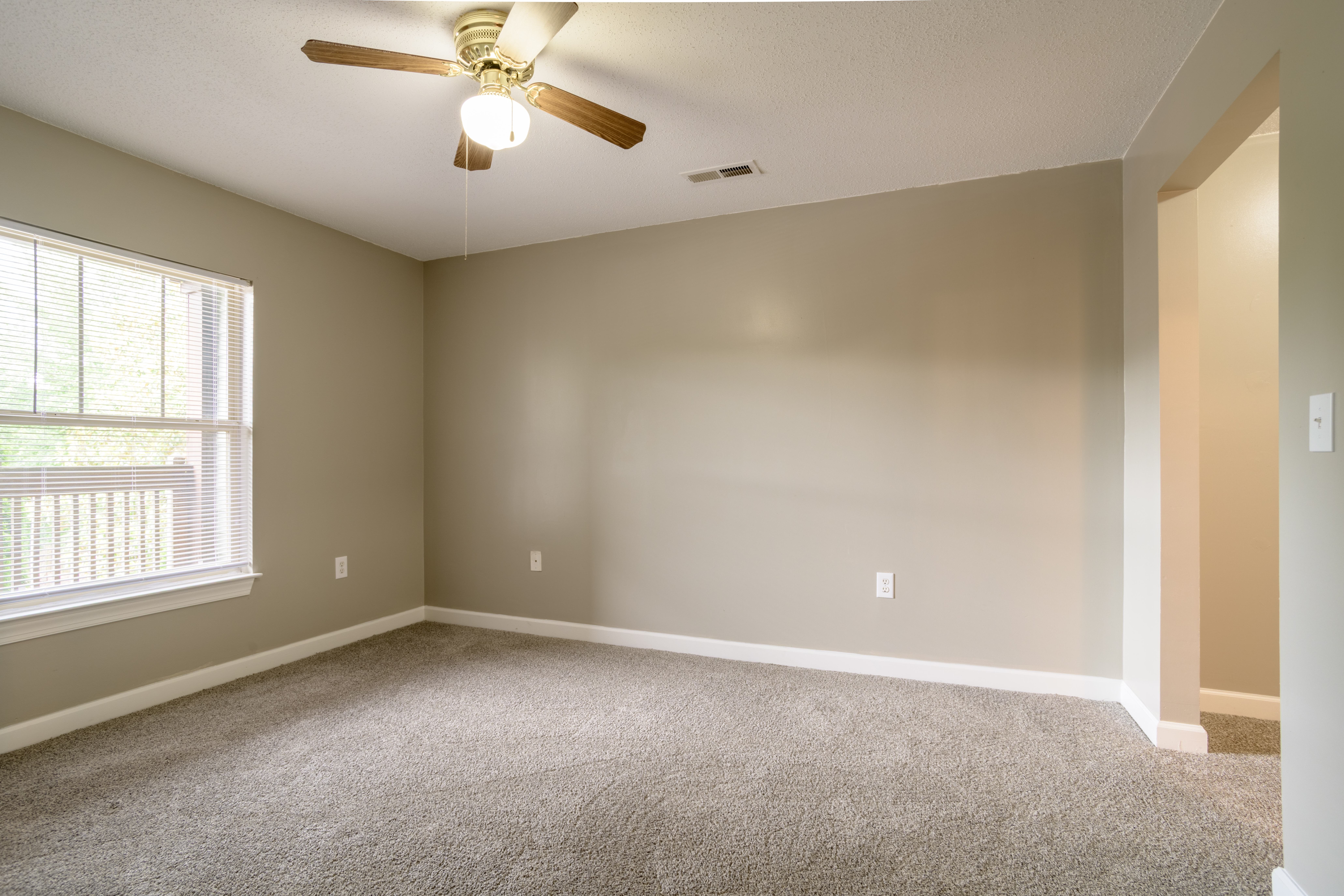 A room with a ceiling fan and carpeted floor.,A room with a ceiling fan and carpeted floor.